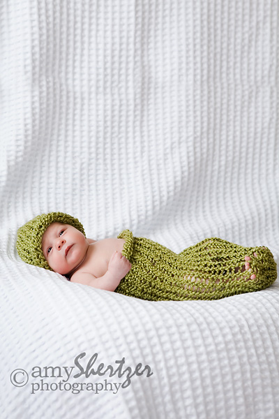 Stretched out baby in green cocoon and hat