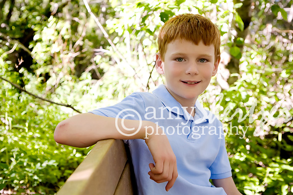 Red headed boy relaxes on a bench in the woods
