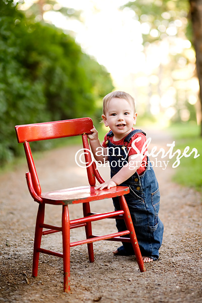 Adorable 1 year old stands by a red chair