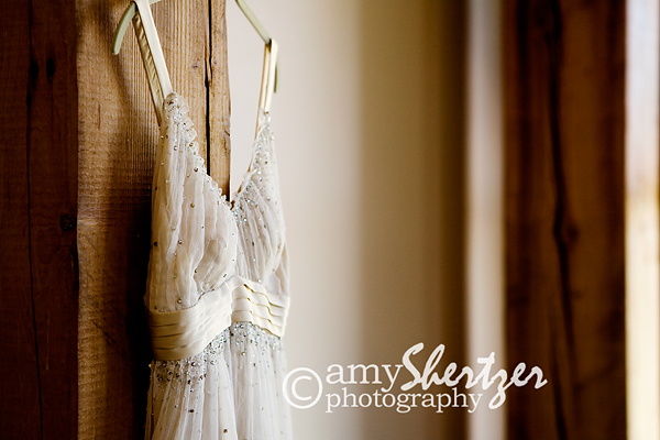 The bridal gown quietly hangs, waiting for the beautiful bride to bring it to life