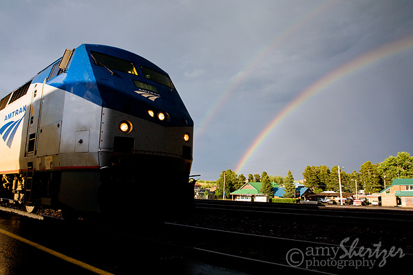 Amtrak train pulls into the station under a double rainbow