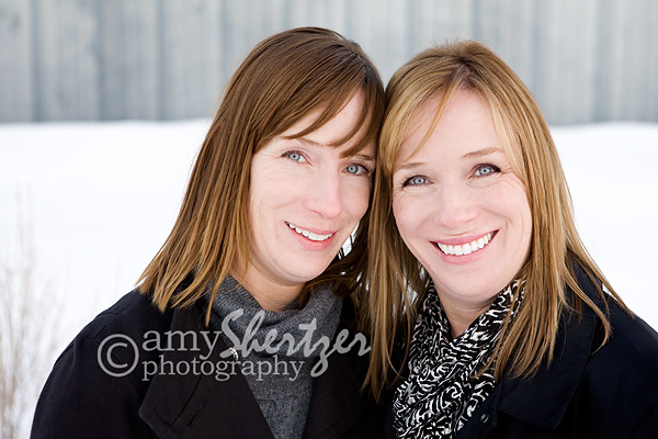 Adult twin sisters pose for a photograph.