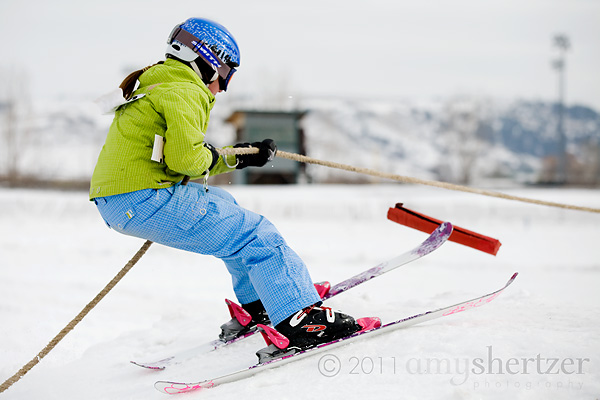 A girl glides up a ramp on skis in part of a skijoring event.
