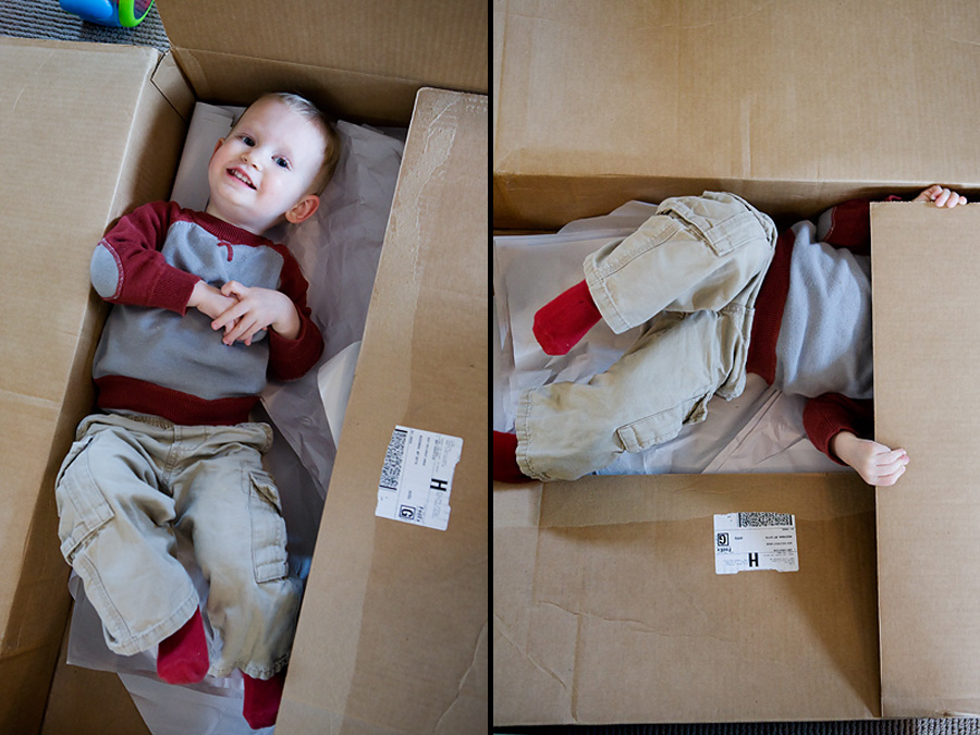 A toddler has fun playing in a large cardboard box.