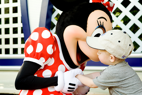 Minnie Mouse gives a kiss to a toddler.