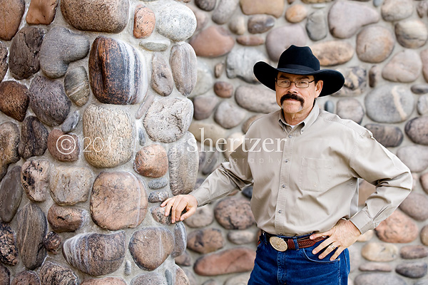 A Bozeman professional poses for a portrait in front of a rock wall.