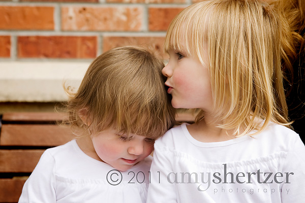 A big sister kisses her little sisters sweetly on the head.