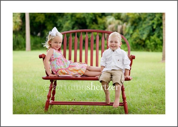 Siblings sit on a bench for a portrait.